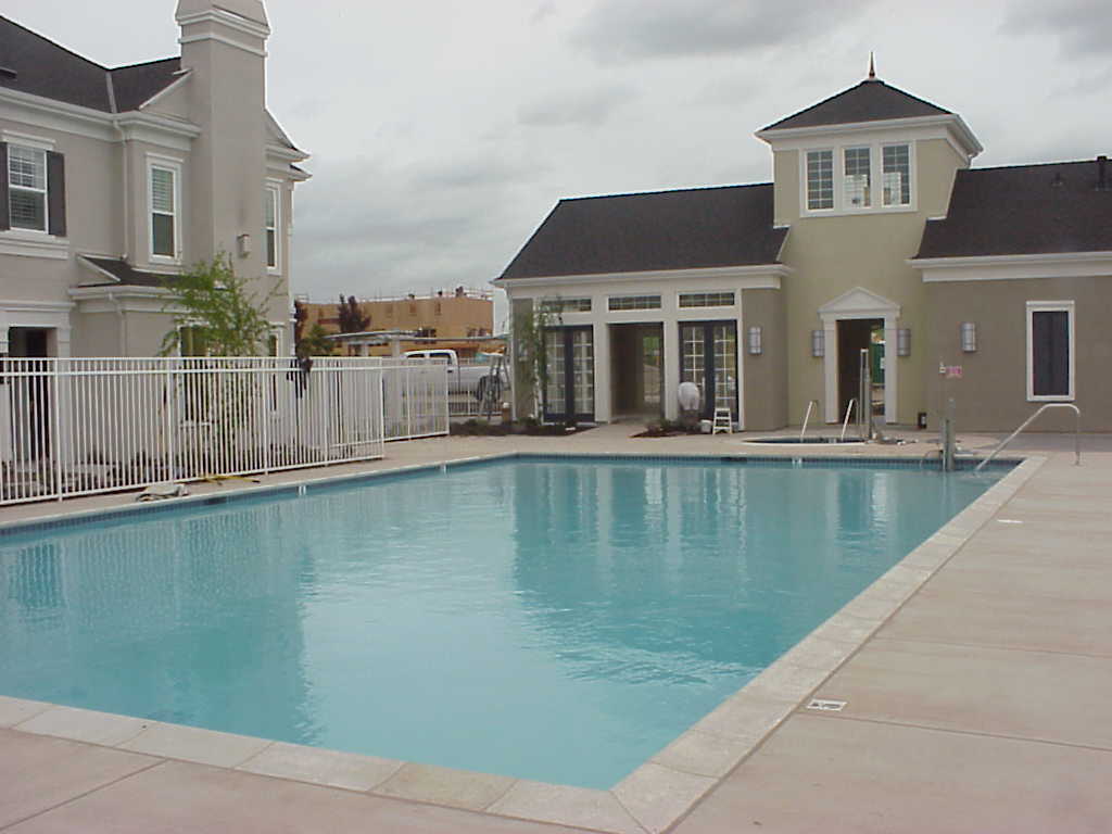 A large swimming pool with a house in the background.