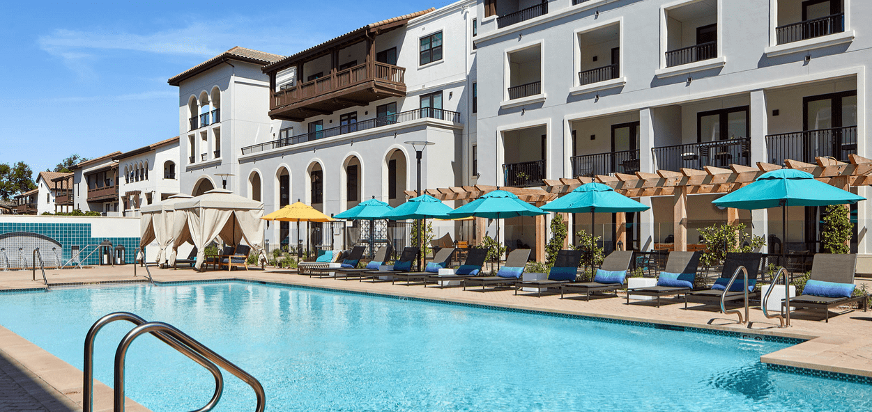 A pool with many chairs and umbrellas next to it