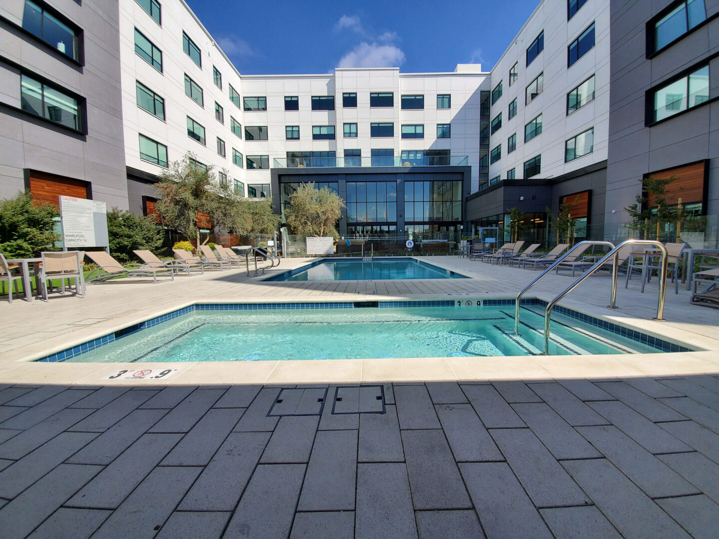 A pool with chairs and umbrellas in the background.