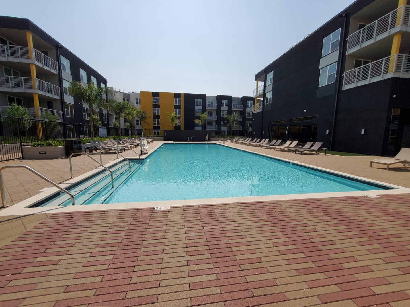 A pool with brick flooring and a large swimming pool.