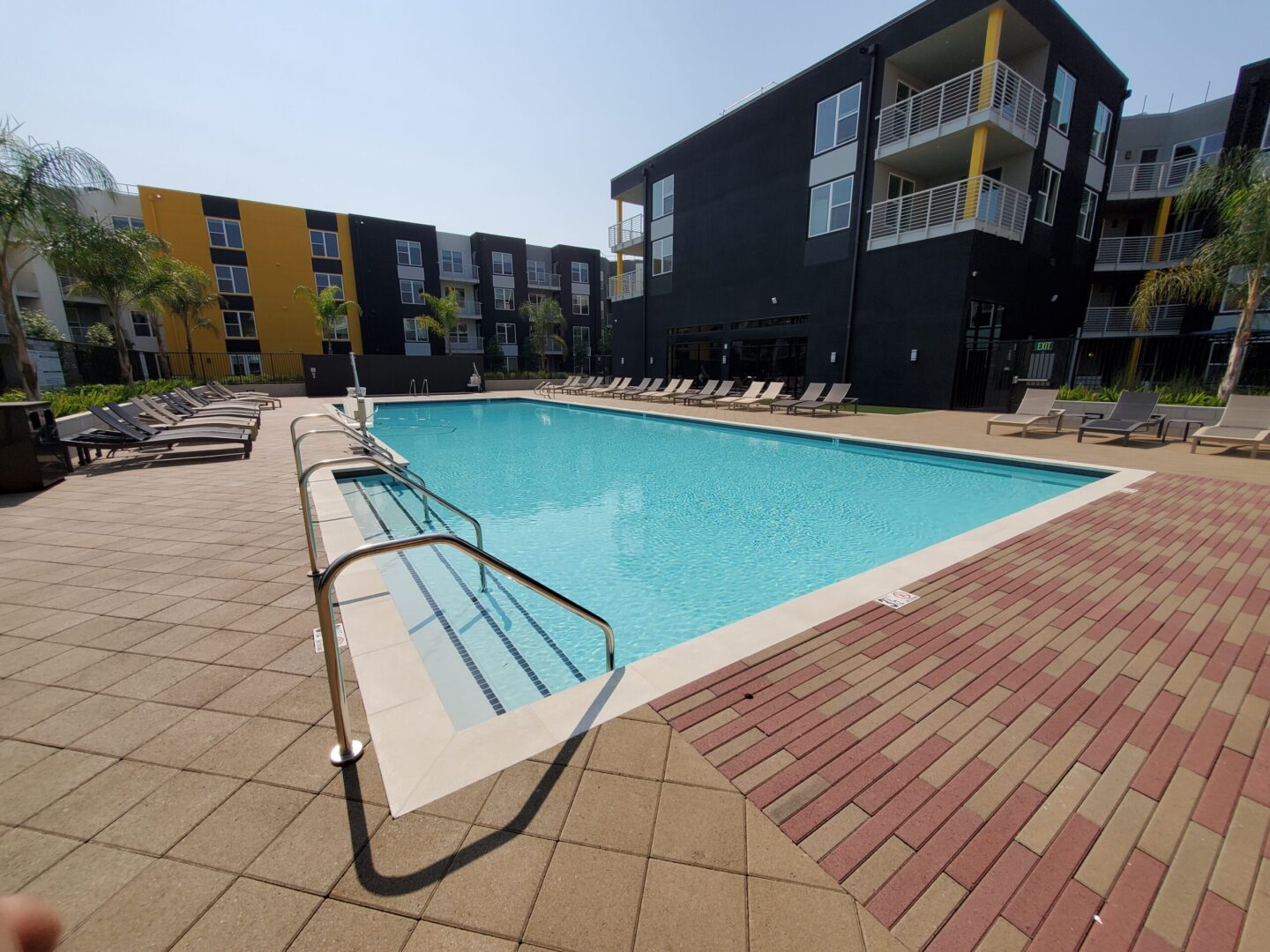 A swimming pool with chairs and umbrellas in the background.