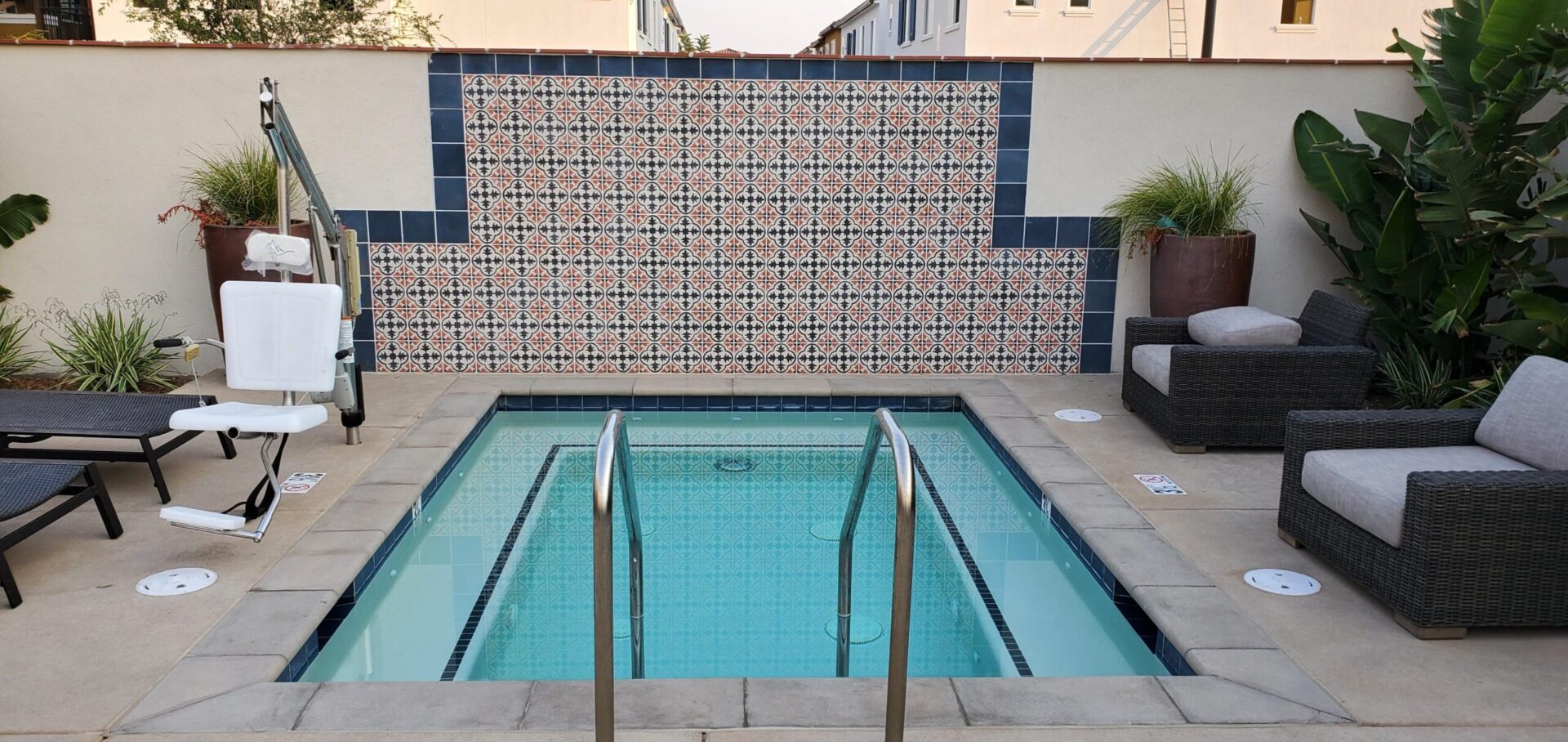 A pool with tile walls and a metal railing.