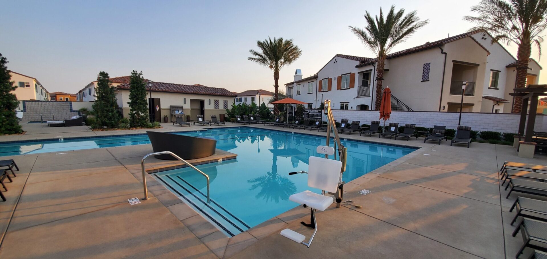 A pool with chairs and umbrellas in the background.